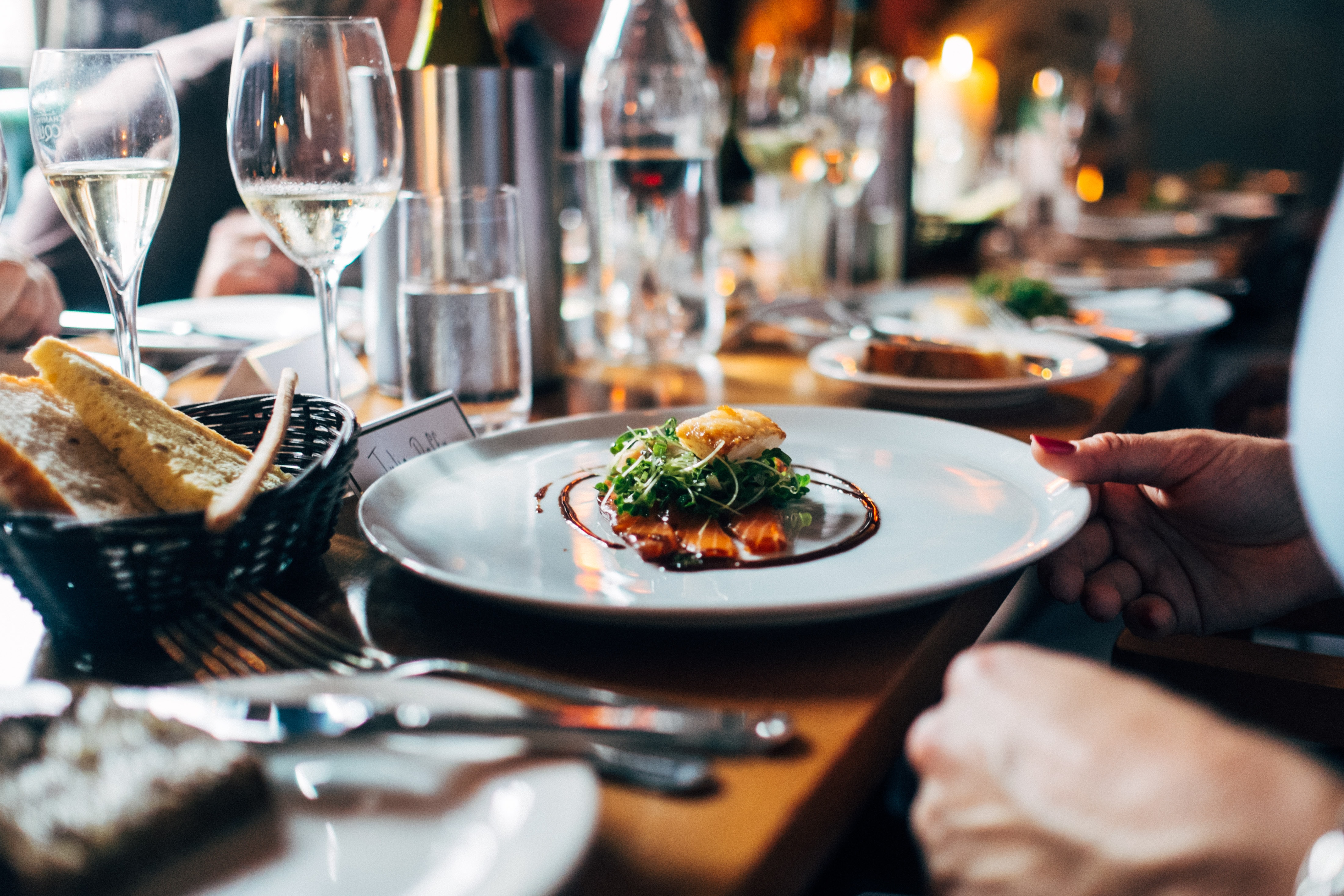 Person with red fingernails holding plate of food in restaurant